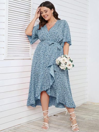 A woman in a blue dress with floral pattern, holding a bouquet of white flowers.